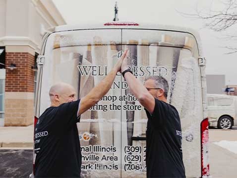 Two men doing a high-five next to the company vehicle