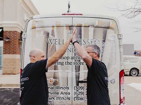 Two men doing a high-five next to the company vehicle